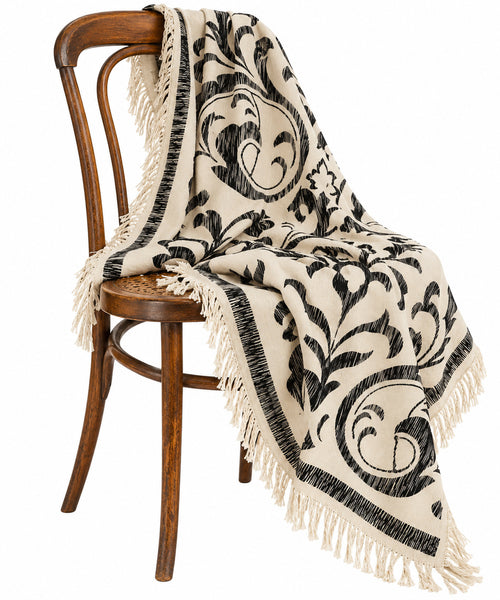 Oversized black and ivory damask square scarf draped over an antique bentwood chair, highlighting the ornamental design and fine Merino wool texture.